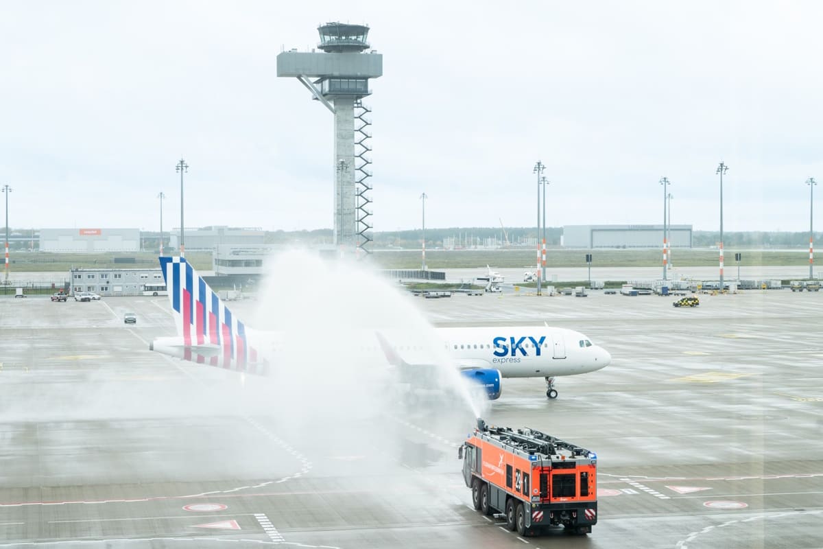 Feuerwehrfahrzeug mit Fontäne über das Flugzeug von SKY express